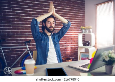 Businessman with eyes closed meditating in creative office - Powered by Shutterstock