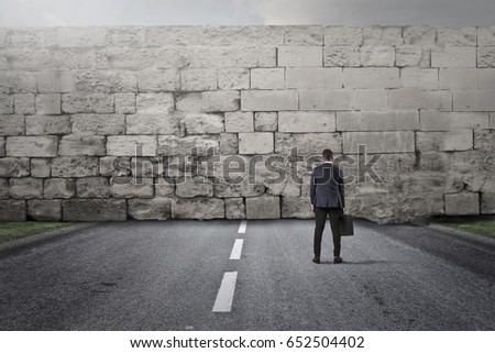 Businessman facing a big stone wall