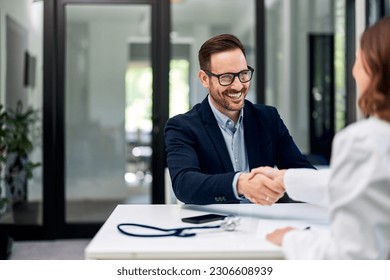 A businessman is feeling happy because a female doctor visited the company and handshaking with her. - Powered by Shutterstock