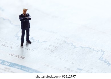 Businessman Figurine Standing Upon A Financial Sector Of A Newspaper