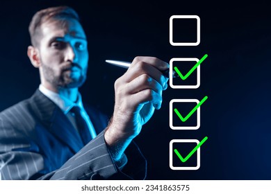 Businessman fills in checkbox. Man ticks box. Guy draws on virtual screen. Concept of maintaining step-by-step plan. Checkbox on invisible display. Businessman in formal suit. Selective focus - Powered by Shutterstock