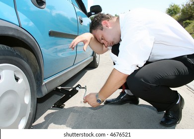 Businessman Fixing Flat Tire On Sunny Day In The Middle Of Nowhere