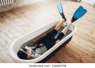 Businessman in flippers and mask lies in bathtub - Shutterstock ID 1140637709