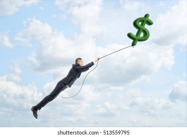 A Businessman Floating Up In The Sky Holding A Big Dollar Sign On A String. Way To Success. Earning Money. Business And Finance.