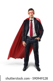 A businessman in a formal suit, a red flowing cape and a red eye mask with one hand in his pocket in front view. Business and success. Self-made people. Self-confidence.