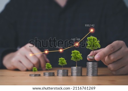 Businessman or fund manager stacking coins with tree plant and increasing graph for growth business investment profit and dividend concept.