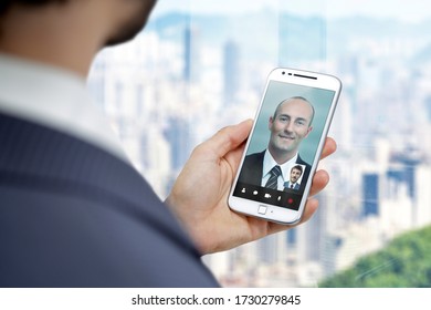 Businessman Getting A Video Call With Another Man In His Mobile Phone. Business Video Conference Through Smartphone.