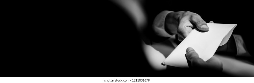 Businessman giving bribe money in the envelope to partner in a corruption scam, panoramic banner black and white tone - Shutterstock ID 1211031679