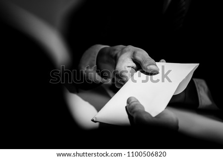 Businessman giving bribe money in the  envelope to partner in a corruption scam with black and white tone