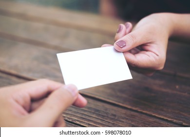 Businessman giving  business card to businesswoman with wooden table background - Powered by Shutterstock