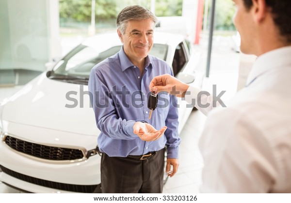 Businessman giving car key to a customer at new
car showroom