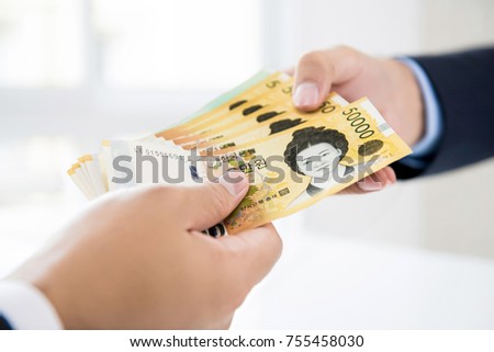 Businessman giving money in form of South Korean Won currency to his partner for service rendered - financial, loan and cash payment concepts