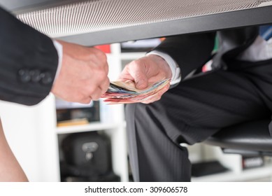 Businessman giving money under a table - Shutterstock ID 309606578