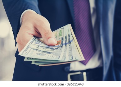 Businessman giving money, united states dollar (USD) bills - cash, payment and financial concepts
