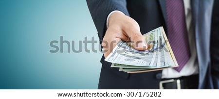Businessman giving money,   united states dollar (USD) bills, on gray background -  panoramic financial background concept