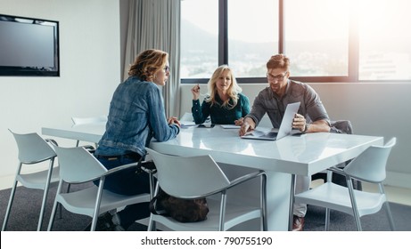 Businessman Giving Presentation To Colleagues At Meeting. Business People At Conference Room Looking At Laptop.