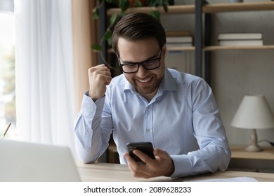 Businessman in glasses sit at desk receive sms feels happy celebrate moment of victory. Career growth and promotion, salary increase, betting, auction monetary win, sincere reaction, triumph concept - Shutterstock ID 2089628233