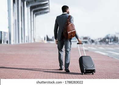 Businessman Going On Business Trip Walking With Travel Suitcase And Backpack Arriving At Airport. Free Space, Back View