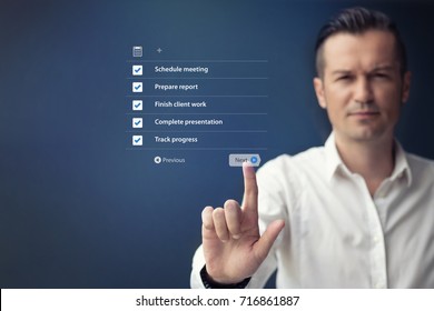 Businessman Going Through To Do List On Virtual Touchscreen. Planning Working Day And Checking Priority's While Making Reminder On Digital Display.