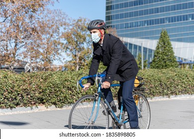 Businessman Going To Work At Office By Bicycle. Handsome Young Man Wears A Surgical Mask. Concept On The Environment And More Sustainable Cities