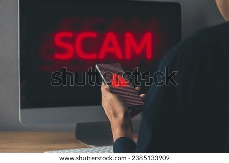 Businessman got scam alert both mobile phone and PC monitor. emergency system hacked  scam alert and cyber security concept.