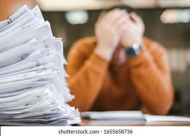 A businessman grabs his head from a pile of papers. The concept of depression from difficulties and possible bankruptcy of an enterprise. - Shutterstock ID 1655658736