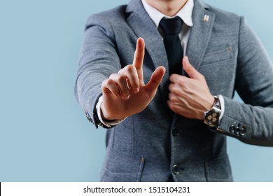 Businessman in a gray suit is making objection gesture by extending hand with the index finger up, holding lapel with his second hand over blue background. Cropped, no head. - Shutterstock ID 1515104231