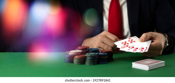 Businessman at green playing table with gambling chips and cards playing poker and blackjack in casino.