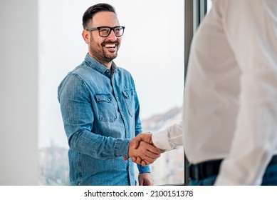 Businessman greeting job applicant businessmen handshaking over signed contract handsome entrepreneur handshake with a colleague cheerful young manager handshake with new employee getting a deal done