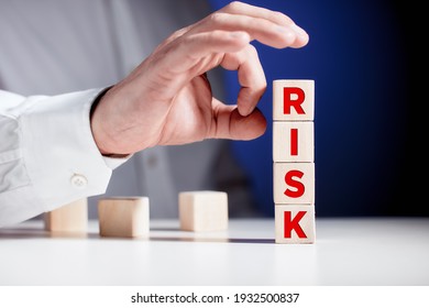 Businessman Hand Is About To Flick The Wooden Cubes With The Word Risk. To Avoid Or Eliminate Risk In Business Finance Decisions.

