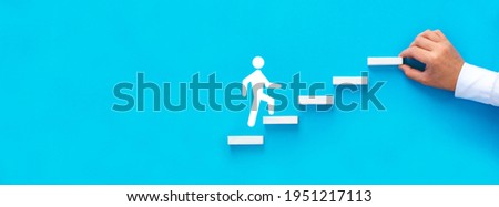 Businessman hand arranging wood block stacking as step stair with figure climb up the ladder of success.  Business start-up, development and success.