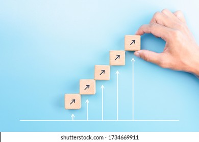 businessman hand arranging wooden blocks stacking as step stair with arrow up on blue background, Business growth success process concept, copy space