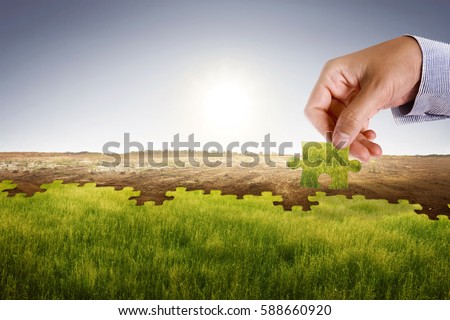 Businessman hand assemble puzzle to build new world with fresh environment. Climate change concept.