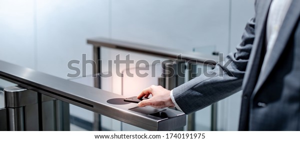 Businessman hand with business wear using\
smartphone to open automatic gate machine in office building.\
Working routine\
concept