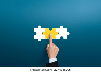 Businessman hand connecting yellow puzzle pieces. joint venture, partnership, Mergers or acquisition concept