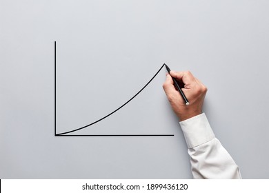 Businessman Hand Drawing A Chart Or Line Graph With An Increasing Slope On Gray Background.