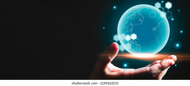 Businessman hand holding blue glowing earth hologram with copy space black background. Business and technology concept. Modern tech and metaverse theme. People and futuristic worldwide innovation