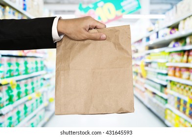 Businessman Hand Holding Brown Paper Bag, With Defocus Aisle Background