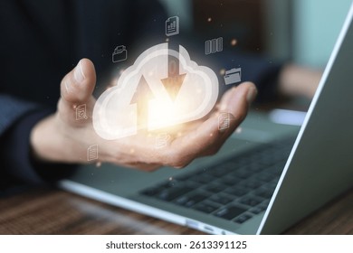 Businessman hand holding with a glowing cloud icon featuring upload and download arrows, and the cloud icon are digital document symbols, cloud computing, data storage, and file transfer technology.
