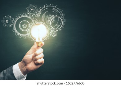 Businessman hand holding light bulb with drawing gears. Teamwork and idea concept - Powered by Shutterstock