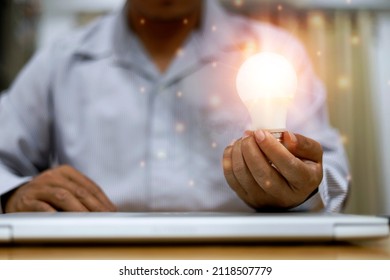 Businessman Hand Holding Lightbulb With Orange Glowing And Connection Online. Creative Thinking Idea Concept.Minister Of Innovation And Innovative Technology,conputer And Technology