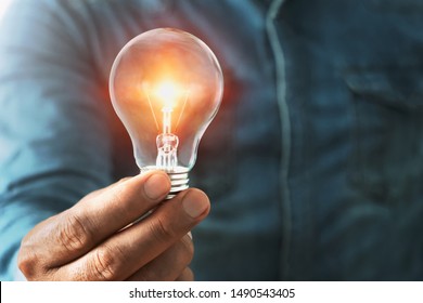 businessman hand holding lightbulb with sunshine. concept saving energy power