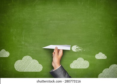 Businessman Hand Holding Paper Plane On Front Of Vintage Full Frame Green Blank Blackboard No Frame And Couple Clouds