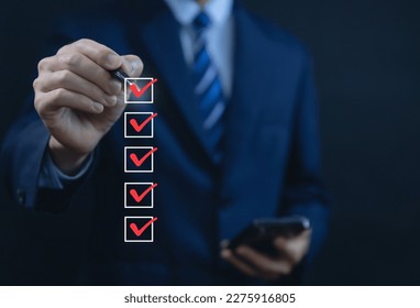 Businessman hand holding a pen ticking a red checkmark on a box in the list Show on the virtual screen. Checklist Ideas in Business Survey items and questionnaires. copy space - Shutterstock ID 2275916805
