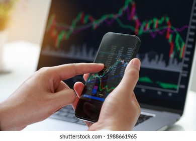 Businessman hand holding phone and analysis finance market graph stock market trading,stock chart and investment concept. - Shutterstock ID 1988661965