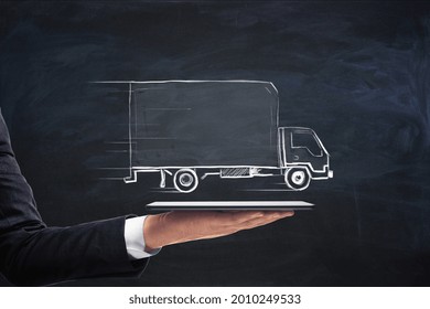 Businessman hand holding tablet with creative truck sketch. Transporation and logistics concept