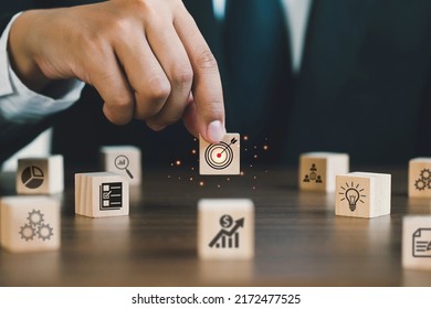 Businessman Hand holding a wooden block target board icon on wooden cube block with icon business strategy. Service concept of business to success Business strategy planning To market victory. - Shutterstock ID 2172477525