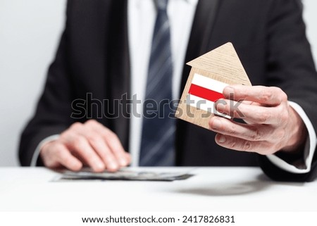 Businessman hand holding wooden Home model with Belorussian flag. insurance and property concepts