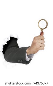 Businessman Hand Investigate Breaking Through A Paper Wall Holding  A Magnifying Glass