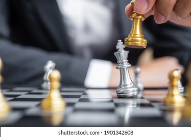businessman hand moving gold Chess King figure and Checkmate enermy or opponent during chessboard competition. Strategy, Success, management, business planning, interruption and leadership concept